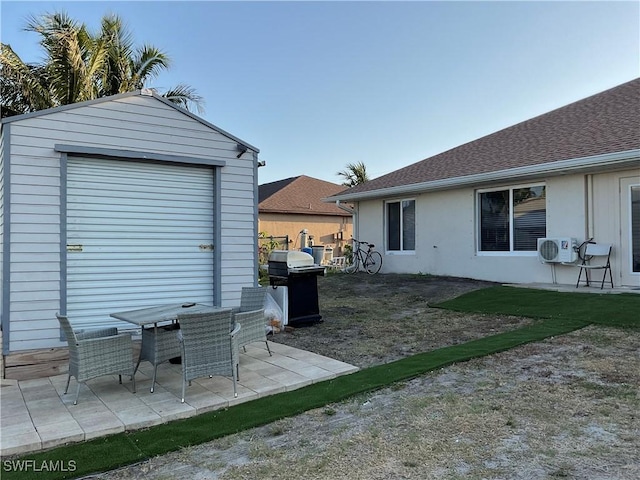 exterior space with ac unit, a shingled roof, a storage shed, an outbuilding, and a patio