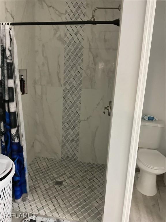 full bathroom featuring toilet and a shower stall