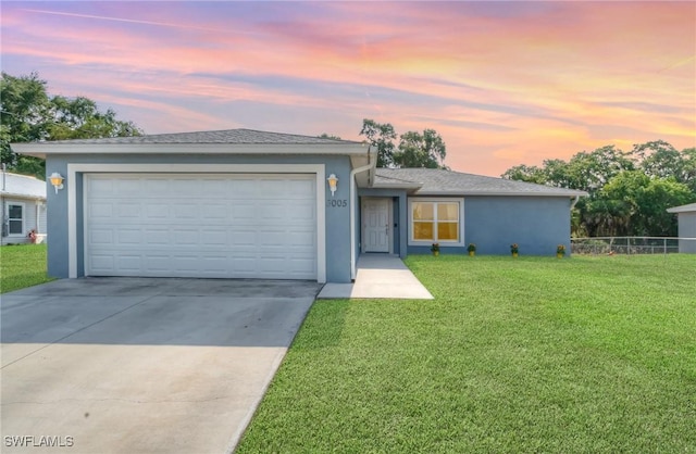 view of front of house featuring a yard, stucco siding, driveway, and a garage