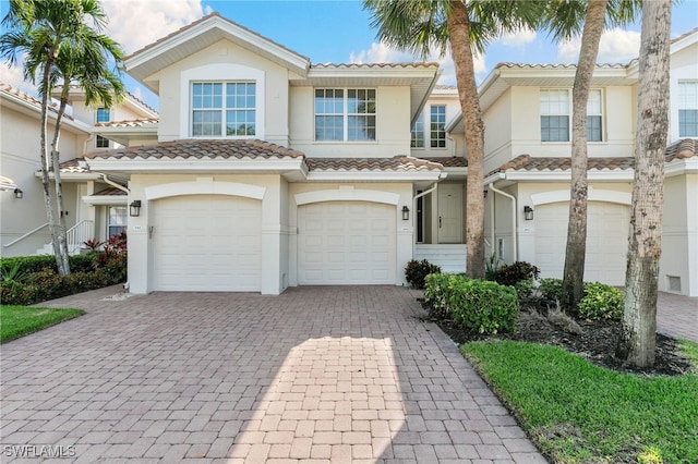 view of front of house featuring a garage, stucco siding, a tile roof, and decorative driveway