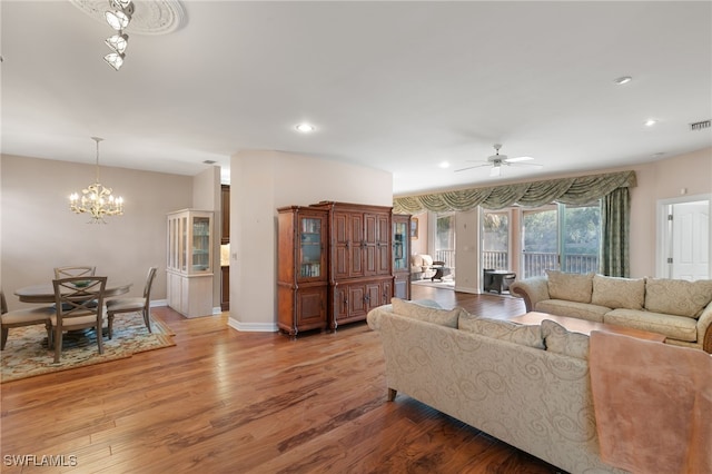living area featuring visible vents, baseboards, ceiling fan with notable chandelier, recessed lighting, and light wood-style flooring