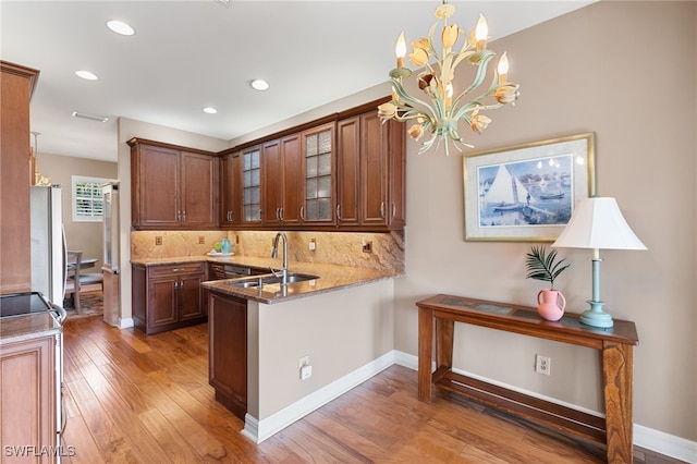 kitchen with fridge, a sink, hardwood / wood-style floors, backsplash, and glass insert cabinets