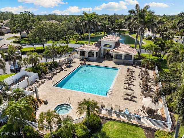 community pool featuring fence, a water view, a hot tub, and a patio area