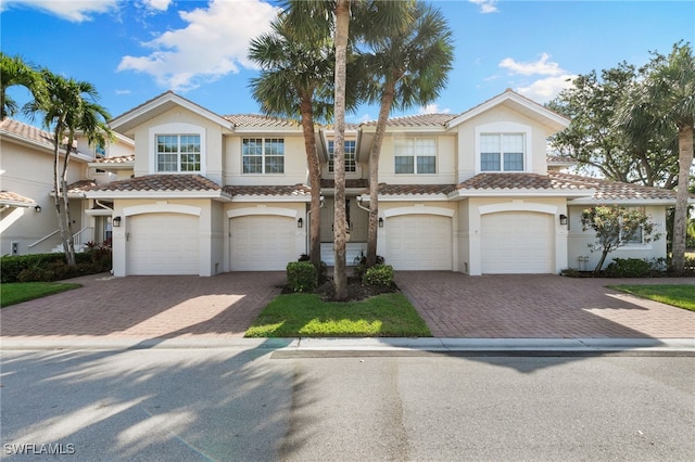 townhome / multi-family property with stucco siding, driveway, and a garage