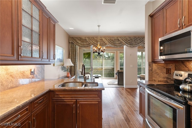 kitchen with a sink, a chandelier, light stone countertops, and stainless steel appliances