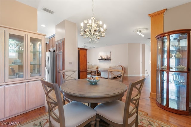 dining space with visible vents, an inviting chandelier, and light wood-style flooring