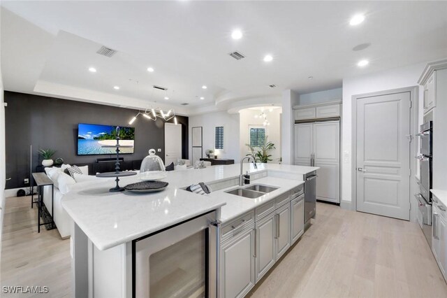 16653 Toscana Cir Unit 704, Naples, FL 34110 - kitchen with a sink, a chandelier, wine cooler, open floor plan, and a kitchen island with sink