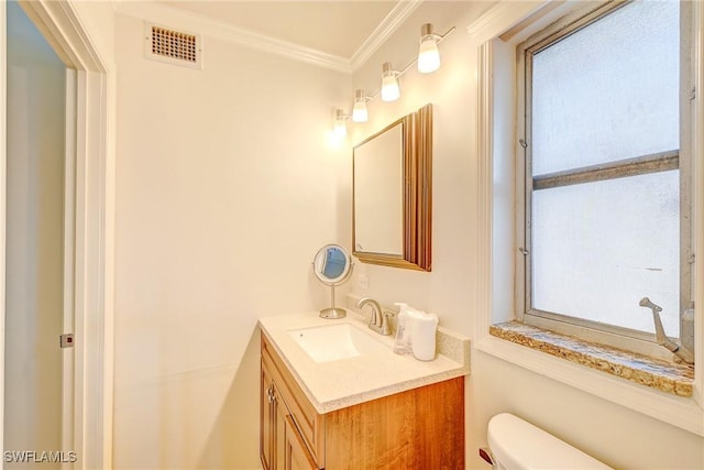 half bathroom with visible vents, toilet, crown molding, and vanity