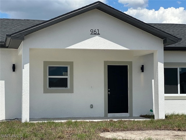 961 Countess Ave, Lehigh Acres, FL 33974 - view of exterior entry with a shingled roof and stucco siding