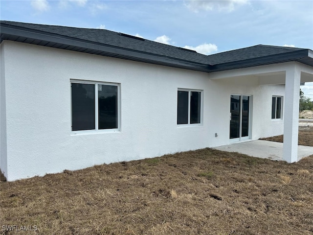 961 Countess Ave, Lehigh Acres, FL 33974 - back of house featuring stucco siding, roof with shingles, and a yard