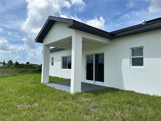 961 Countess Ave, Lehigh Acres, FL 33974 - back of house featuring stucco siding, a patio area, and a yard