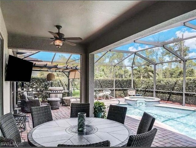 view of patio / terrace featuring outdoor dining space, ceiling fan, glass enclosure, and a pool with connected hot tub