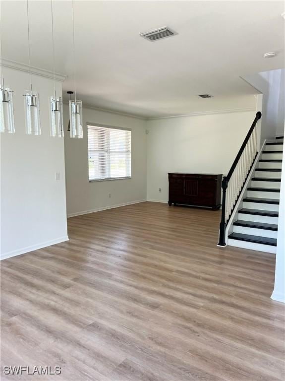 unfurnished living room with stairs, visible vents, light wood-style flooring, and baseboards