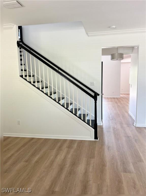 stairs with visible vents, wood finished floors, and baseboards