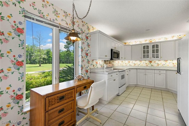 105 Wilderness Dr Unit B105, Naples, FL 34105 - kitchen featuring stainless steel microwave, white electric range oven, glass insert cabinets, light countertops, and wallpapered walls