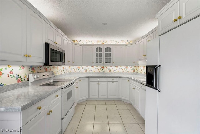 105 Wilderness Dr Unit B105, Naples, FL 34105 - kitchen featuring a textured ceiling, white cabinetry, glass insert cabinets, light countertops, and white appliances
