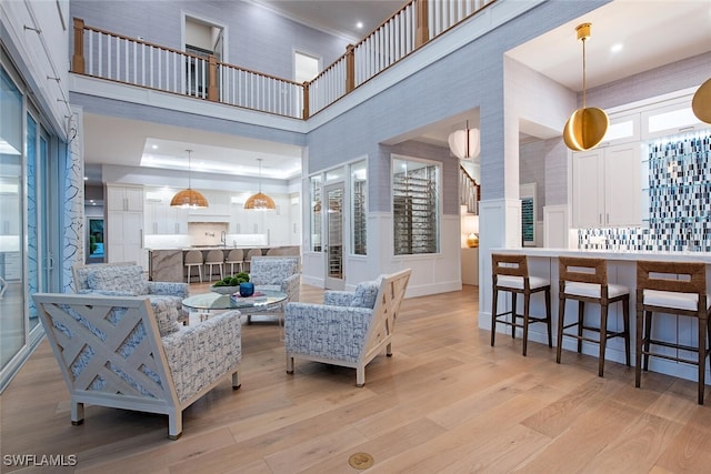 188 W St, Naples, FL 34108 - living room featuring a towering ceiling, light wood-style floors, ornamental molding, and recessed lighting
