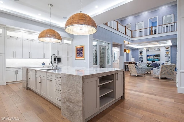 188 W St, Naples, FL 34108 - kitchen with a sink, a center island with sink, a high ceiling, recessed lighting, and light wood-style flooring