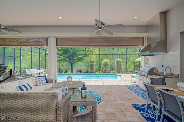 pool featuring a sink, a patio area, glass enclosure, ceiling fan, and grilling area