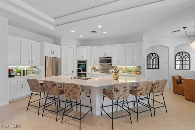 kitchen with appliances with stainless steel finishes, a sink, visible vents, and tasteful backsplash