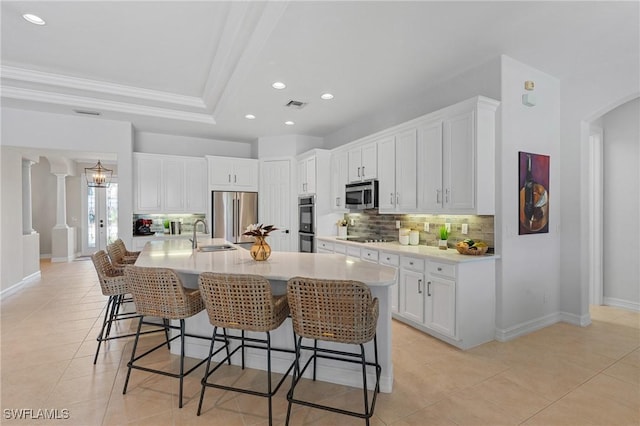 kitchen featuring a kitchen breakfast bar, appliances with stainless steel finishes, visible vents, and tasteful backsplash