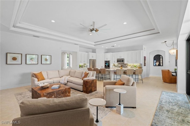 living area featuring recessed lighting, arched walkways, a tray ceiling, a ceiling fan, and light tile patterned floors