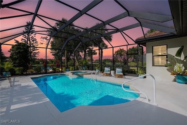 pool at dusk featuring a patio, glass enclosure, and a pool with connected hot tub
