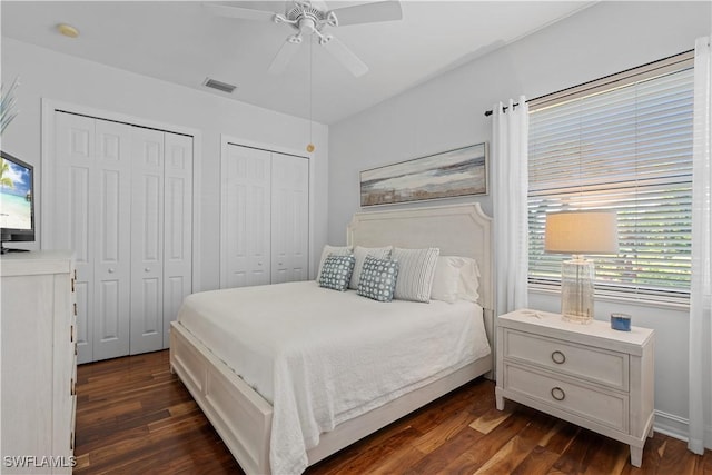 bedroom featuring visible vents, multiple closets, and dark wood-type flooring