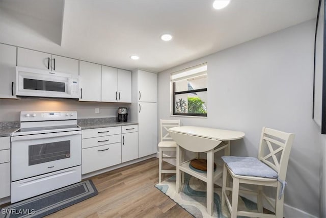 527 Lake Louise Cir Unit 101, Naples, FL 34110 - kitchen with dark countertops, light wood-type flooring, white cabinetry, recessed lighting, and white appliances