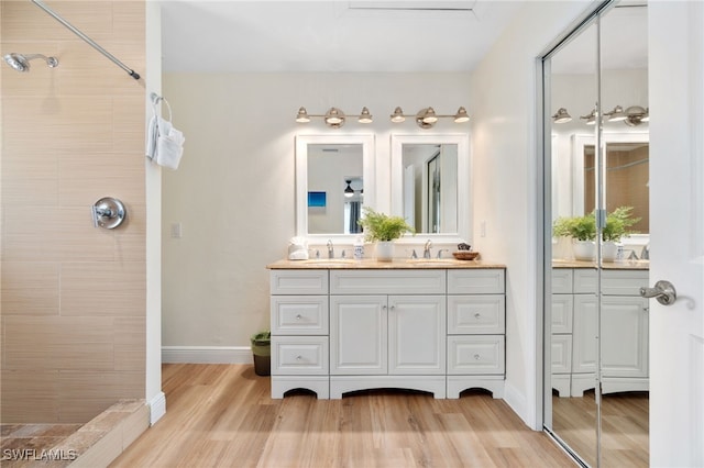 3565 Balboa Cir W, Naples, FL 34105 - bathroom with a tile shower, baseboards, wood finished floors, and vanity