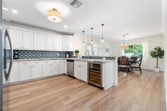 3565 Balboa Cir W, Naples, FL 34105 - kitchen featuring appliances with stainless steel finishes, visible vents, light wood finished floors, wine cooler, and a peninsula