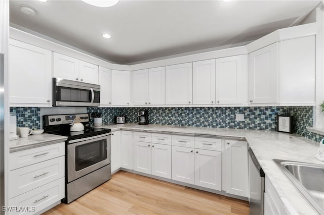 3565 Balboa Cir W, Naples, FL 34105 - kitchen with white cabinetry, stainless steel appliances, backsplash, and a sink