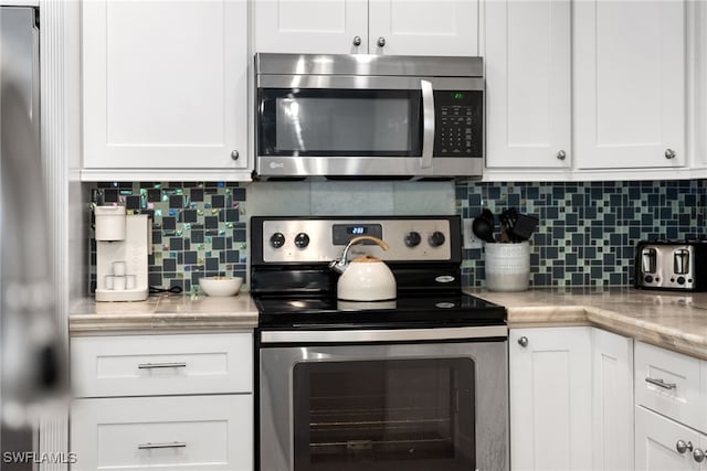 3565 Balboa Cir W, Naples, FL 34105 - kitchen with backsplash, white cabinets, and appliances with stainless steel finishes