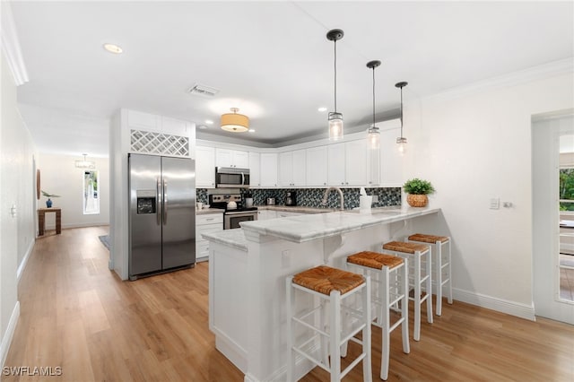 3565 Balboa Cir W, Naples, FL 34105 - kitchen with appliances with stainless steel finishes, a breakfast bar area, a peninsula, and light wood finished floors