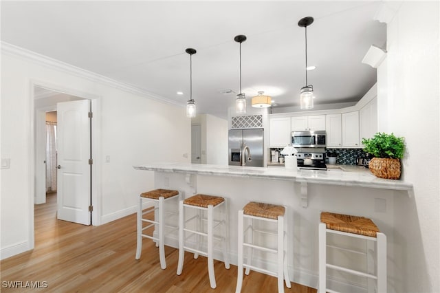 3565 Balboa Cir W, Naples, FL 34105 - kitchen with white cabinetry, stainless steel appliances, baseboards, a peninsula, and backsplash