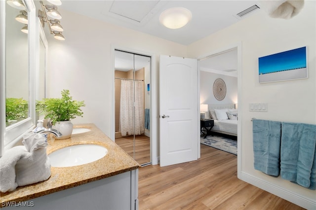 3565 Balboa Cir W, Naples, FL 34105 - bathroom with a sink, connected bathroom, double vanity, visible vents, and wood finished floors