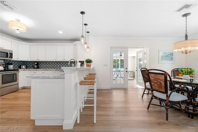 3565 Balboa Cir W, Naples, FL 34105 - kitchen featuring a breakfast bar area, visible vents, a peninsula, light countertops, and appliances with stainless steel finishes