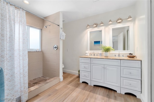 3565 Balboa Cir W, Naples, FL 34105 - bathroom with a sink, toilet, a tile shower, double vanity, and wood finished floors