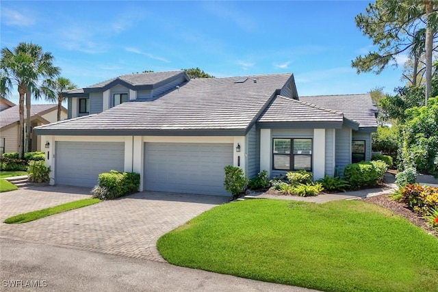 view of front of house with a front lawn, decorative driveway, stucco siding, an attached garage, and a tile roof
