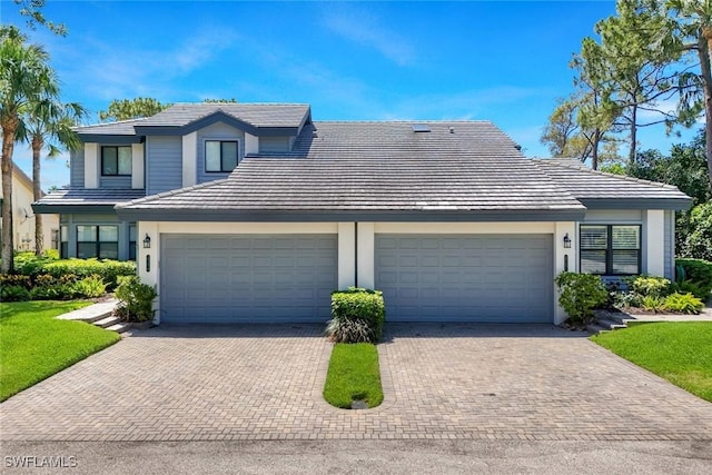 view of front of property with a tiled roof, decorative driveway, an attached garage, and stucco siding