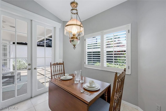 dining space featuring light tile patterned flooring, an inviting chandelier, french doors, baseboards, and lofted ceiling