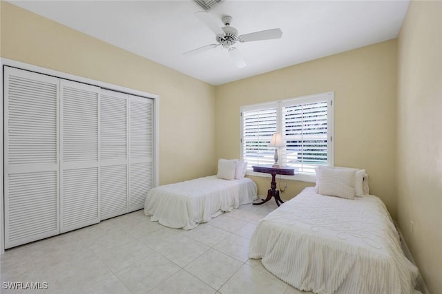 tiled bedroom with a ceiling fan and a closet