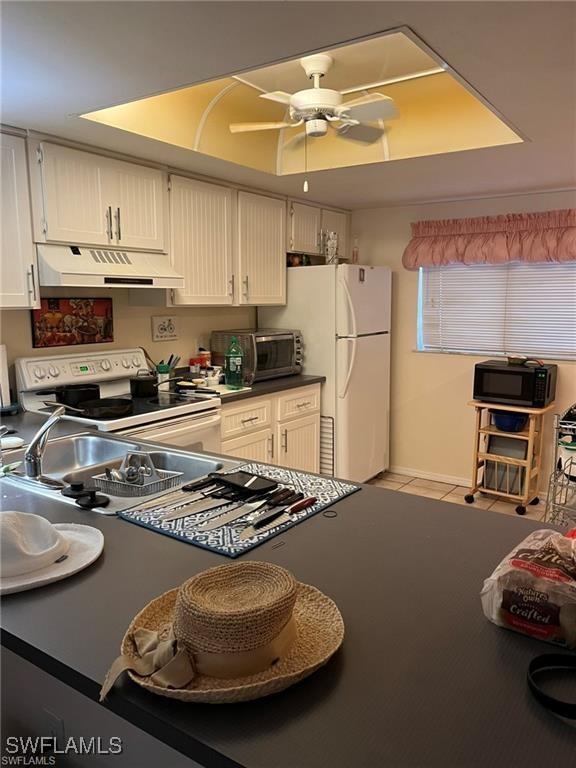 2385 Naples Trace Cir Unit 1, Naples, FL 34109 - kitchen featuring dark countertops, white appliances, ceiling fan, under cabinet range hood, and light tile patterned floors