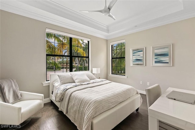 bedroom with crown molding, baseboards, a tray ceiling, and dark wood finished floors