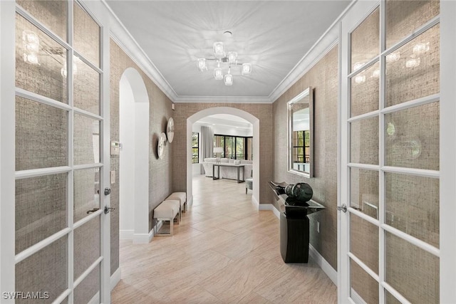 hallway with french doors, arched walkways, a chandelier, and ornamental molding