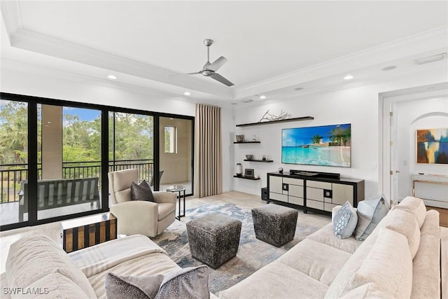 living room with a ceiling fan, a tray ceiling, ornamental molding, and a wealth of natural light