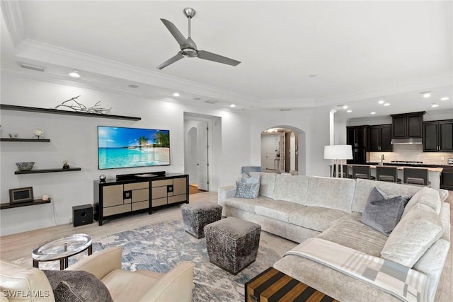living area with recessed lighting, arched walkways, a ceiling fan, and ornamental molding