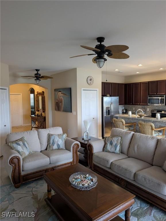 living room featuring a ceiling fan and arched walkways