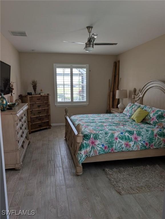 bedroom featuring light wood finished floors, visible vents, ceiling fan, and baseboards