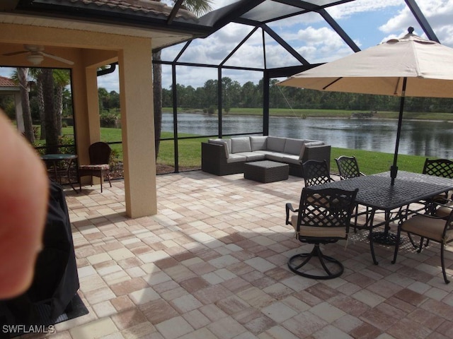 view of patio featuring an outdoor hangout area, a water view, glass enclosure, outdoor dining space, and ceiling fan